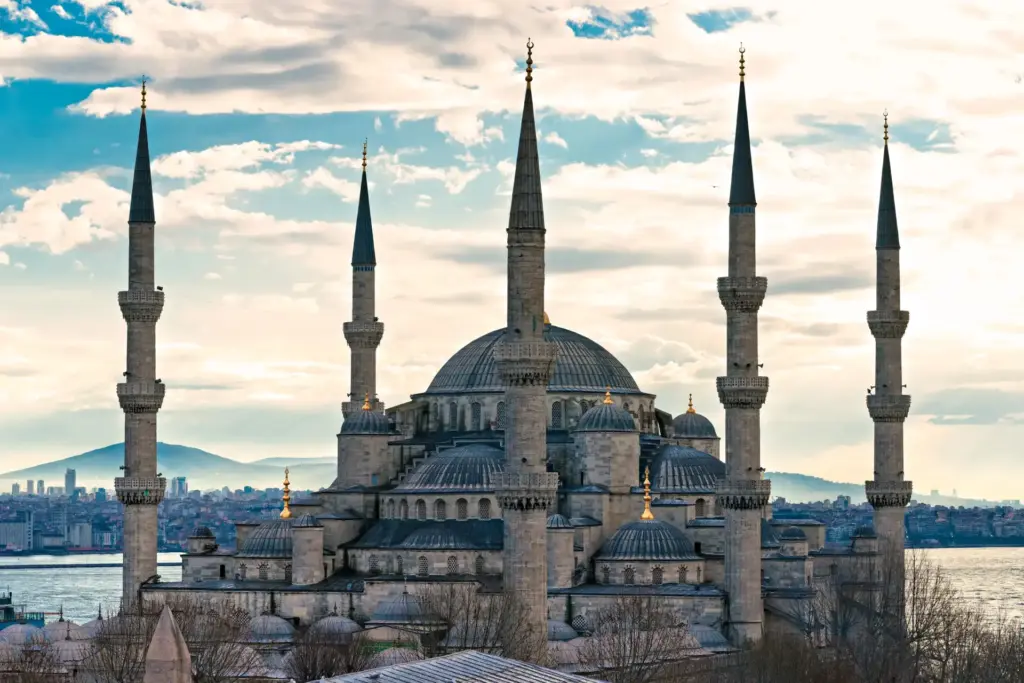 Exterior view of the Blue Mosque in Istanbul showing its iconic six minarets and cascading domes against a cloudy sky