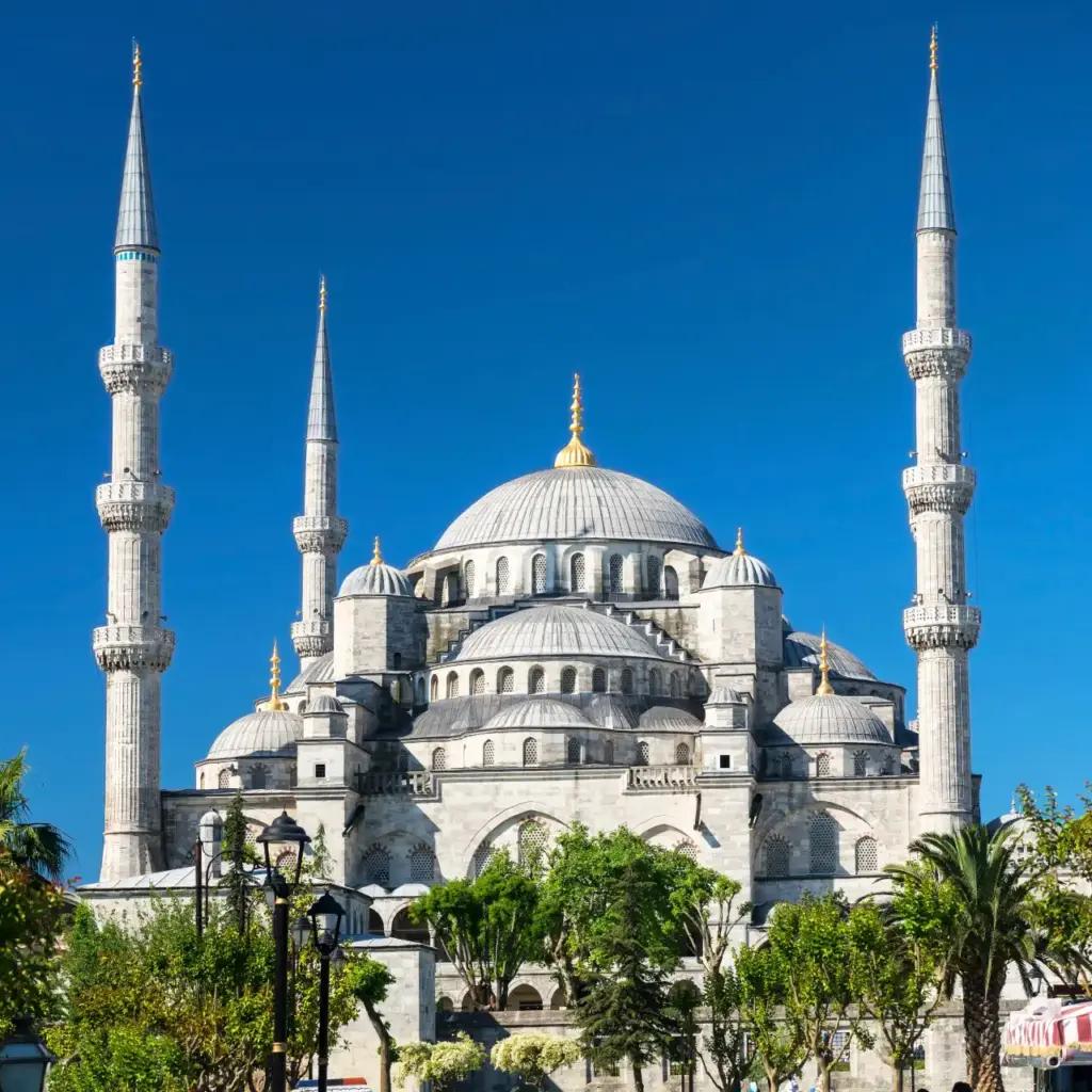 Front view of the Blue Mosque from Sultanahmet Square showing the full façade with six minarets, central dome, and garden forecourt